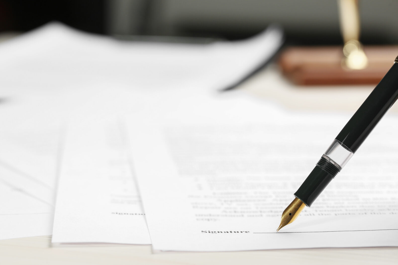 Signing notary document with fountain pen at light table, closeup. Space for text