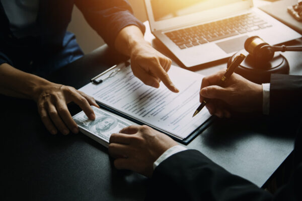 Justice and Law concept. Legal counsel presents to the client a signed contract with gavel and legal law or legal having team meeting at law firm in background